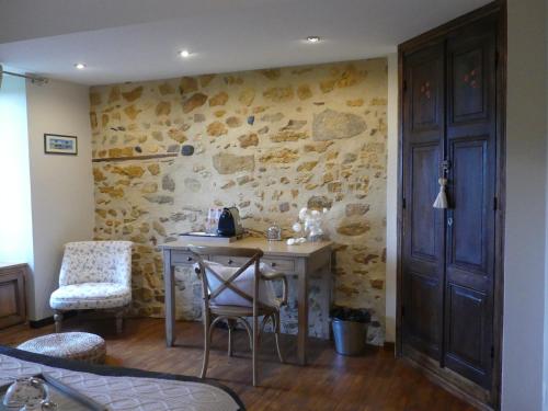Cette chambre dispose d'un bureau et d'un mur en pierre. dans l'établissement la maison de roussi, à Nonette