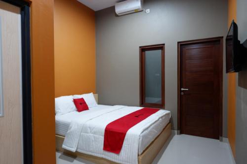 RedDoorz Syariah near Stasiun Tegal في تيغال: غرفة نوم بسرير وبطانية حمراء