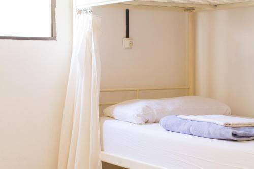 a bedroom with a bed with white sheets and a window at Casa Grande Surf Hostel in El Médano