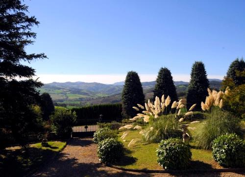 a garden with bushes and trees and a mountain at Villa La Palazzina in Agazzano