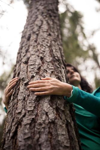a woman hugging a tree with her hands on it at Tonzhaus Hotel in Senales