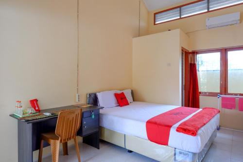 een slaapkamer met een bed en een bureau bij RedDoorz Syariah near Alun Alun Purwokerto in Purwokerto