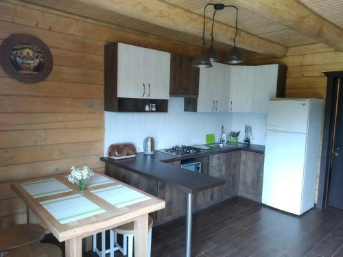 a kitchen with white cabinets and a table and a refrigerator at Пагорб Їжака / Hedgehog Hill in Yablunytsya