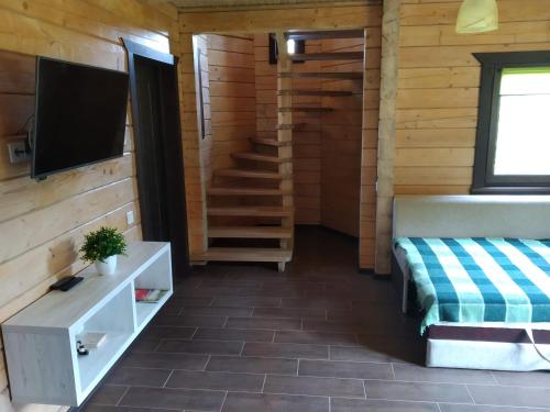a room with a tv and a staircase in a cabin at Пагорб Їжака / Hedgehog Hill in Yablunytsya