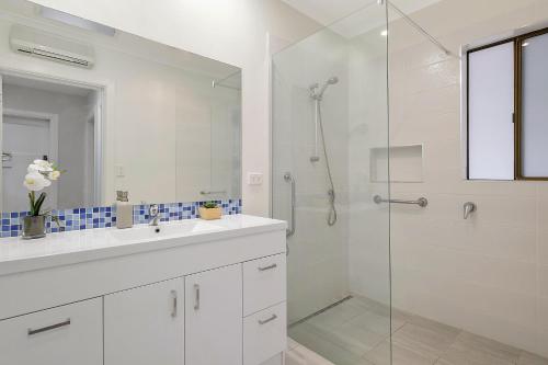 Un baño blanco con ducha y lavabo. en East Coast Hideaway Beach Retreat, en Orford
