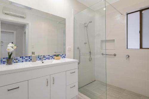 a white bathroom with a shower and a sink at East Coast Hideaway Beach Retreat in Orford