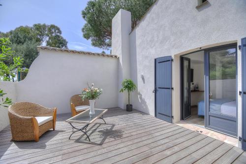 a patio with a table and chairs on a wooden deck at Le Refuge - Gigaro Lodges in La Croix-Valmer