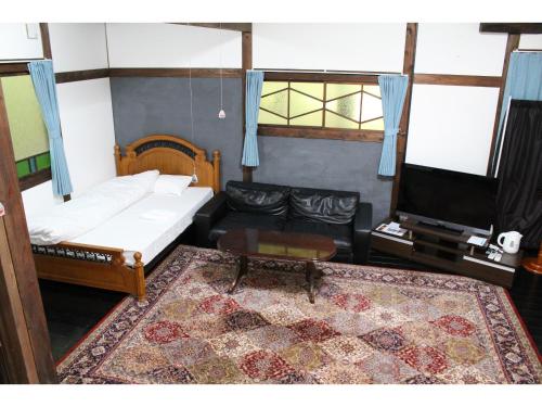 a living room with a couch and a tv at Kotohira Guest House en in Hita