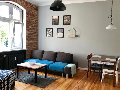 a living room with a blue couch and a table at Apartament Odrzanka in Gryfino