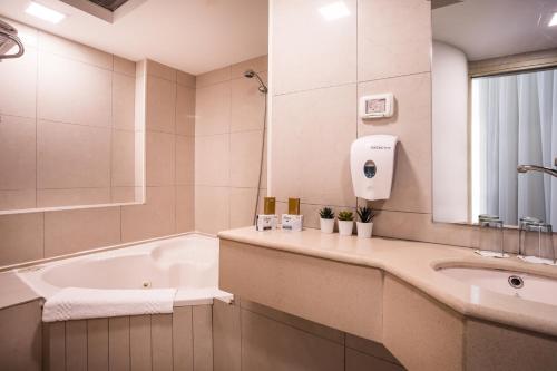 a bathroom with a tub and a sink at Satori Hotel in Haifa