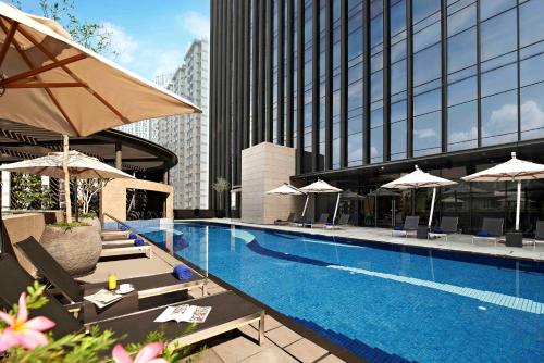 uma piscina com guarda-sóis e cadeiras e um edifício em Carlton City Hotel Singapore em Singapura