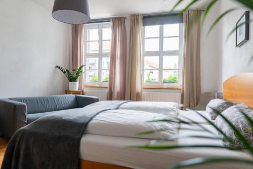 1 dormitorio con cama, sofá y ventanas en Altstadtbleibe, en Naumburg