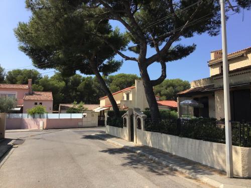 une rue en face d'une maison avec un arbre dans l'établissement Studio Sausset les pins, à Sausset-les-Pins