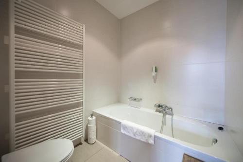 a white bathroom with a toilet and a tub at Saint-Gangulphe in Liège