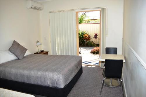 ein Schlafzimmer mit einem Bett, einem Tisch und einem Stuhl in der Unterkunft Redland Bay Motel in Redland Bay