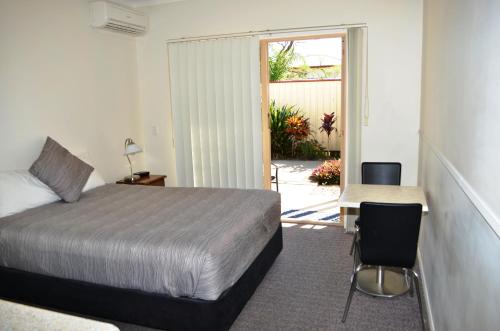 a bedroom with a bed and a table and a chair at Redland Bay Motel in Redland Bay