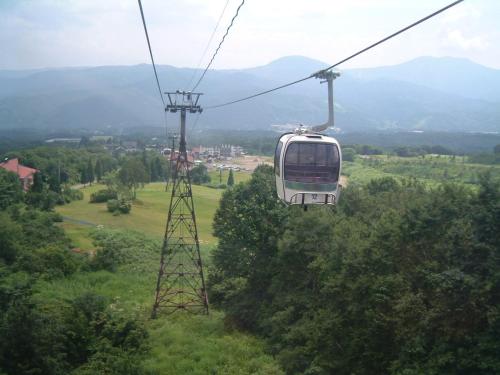 a cable car flying over a green field at Akakura Wakui Hotel in Myoko
