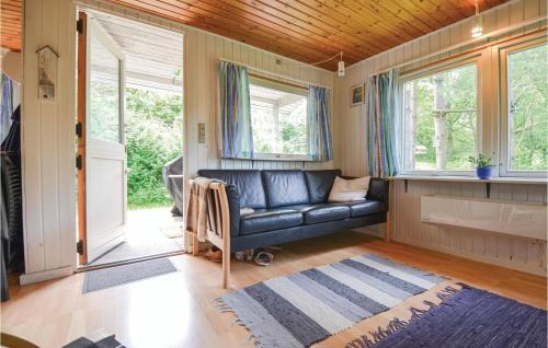 a living room with a black leather couch and windows at 2 Bedroom Nice Home In Ebeltoft in Ebeltoft