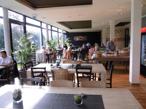 a restaurant with tables and people sitting at tables at Campushotel in Hagen