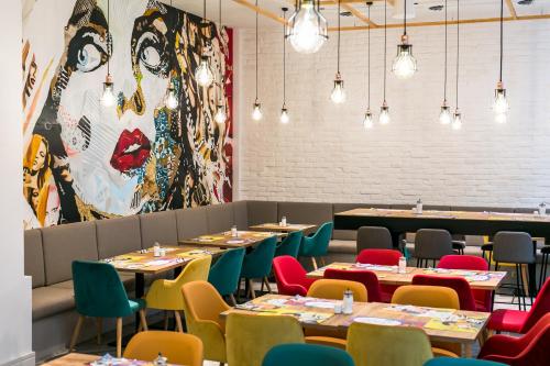 a dining room with tables and chairs and a large mural at T62 Hotel in Budapest