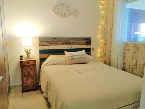 a bedroom with a bed with a wooden headboard and a lamp at A l' orée de l'ô in La Ciotat