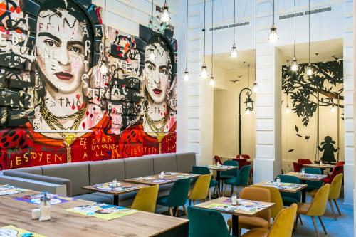 a restaurant with tables and chairs and a large mural at T62 Hotel in Budapest