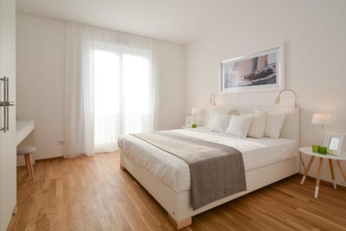 a white bedroom with a white bed and a window at Lunas Appartements Essen in Essen