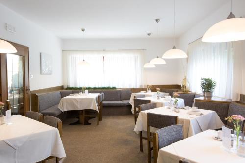 a restaurant with tables and chairs with white tablecloths at Pension Sankt Urban in Merano