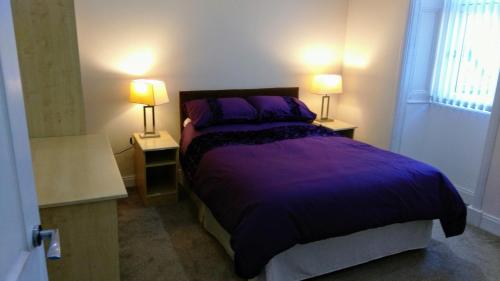 a bedroom with a purple bed and two lamps at CASTLEBANK HOUSE FLATS, DINGWALL in Dingwall