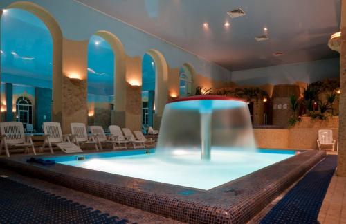 a swimming pool in a building with a fountain at Foresta Festival Park in Prokhorovo