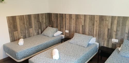 two twin beds in a room with wooden walls at Pensión La Estrella in Zaragoza