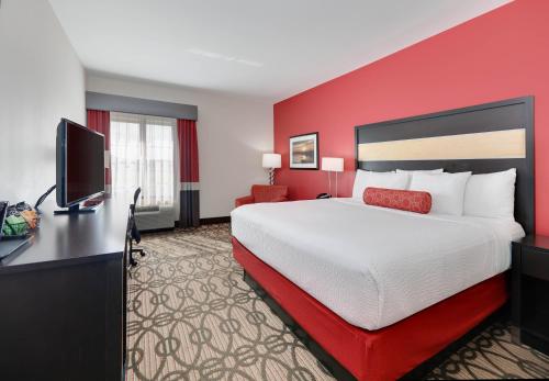 a hotel room with a large bed and a flat screen tv at La Quinta by Wyndham Starkville at MSU in Starkville