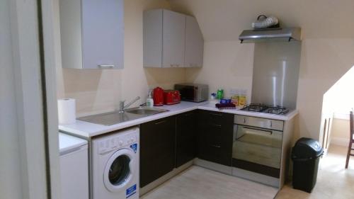 a small kitchen with a sink and a washing machine at CASTLEBANK HOUSE FLATS, DINGWALL in Dingwall