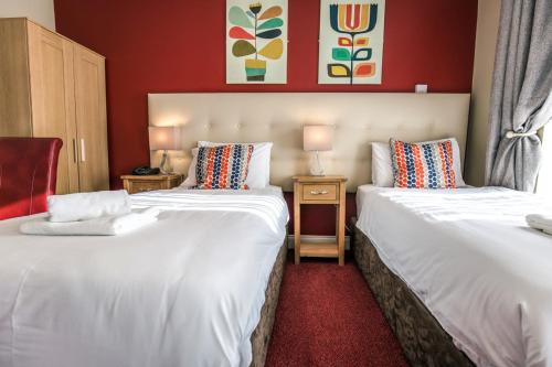 twee bedden in een kamer met rode muren bij Mc Kevitts Village Hotel in Carlingford