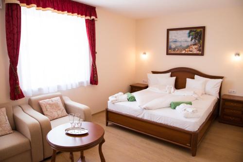 シオーフォクにあるLuxury Hotel Siófokのベッドルーム1室(ベッド1台、ソファ、テーブル付)
