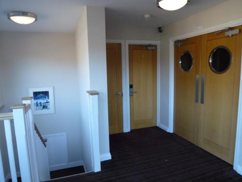 a hallway with two wooden doors and a staircase at Boathouse Hotel in Hythe