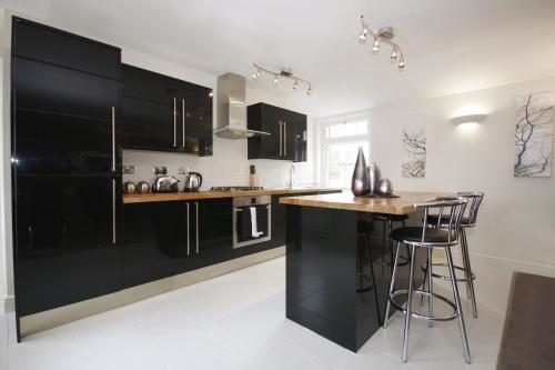 a kitchen with black cabinets and a counter with bar stools at Montague House in Wokingham