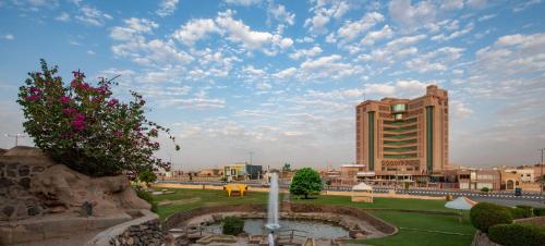 a building with a fountain in front of a building at Ramada Hotel & Suites by Wyndham Al Qassim in Al Bukayriyah