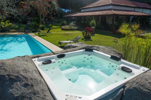a bath tub sitting on a rock next to a swimming pool at Hotel Fazenda Bela Riba in Barrinha