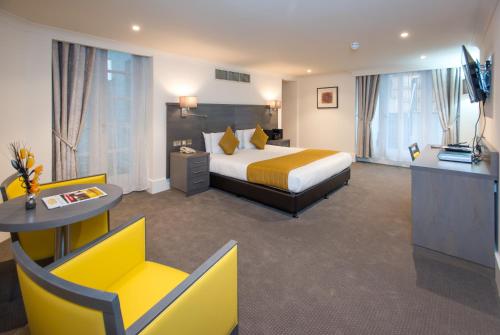 a hotel room with a king sized bed and a television at The Park City Grand Plaza Kensington Hotel in London