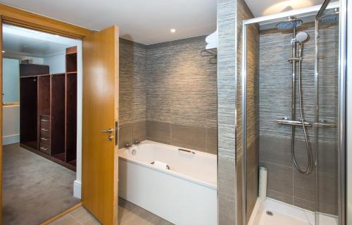 a bathroom with a tub, toilet and shower at The Park City Grand Plaza Kensington Hotel in London