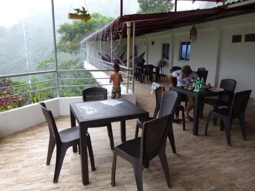 a man sitting at a table on a balcony at Hostal Alto de la Montaña in Minca