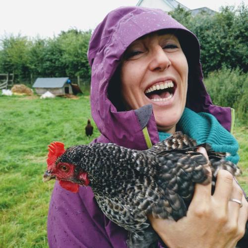 a woman holding a chicken in a field at Bastle Retreats Farm Cottage in Duns