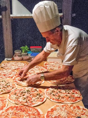 a chef preparing pizzas on a table in a kitchen at Agriturismo Selvella in Radicofani