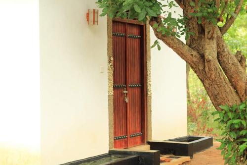 a red door on the side of a building with a tree at Grand freedom in Sigiriya