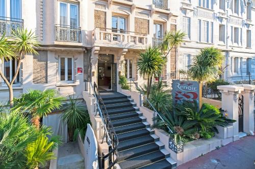 a building with stairs in front of it with palm trees at Hotel Renoir in Cannes