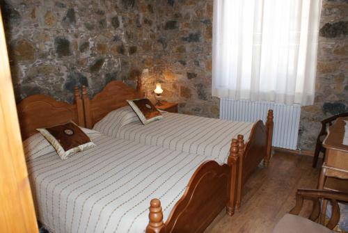 two beds in a bedroom with a stone wall at ATRATSA Mountain Suites in Kalopanayiotis