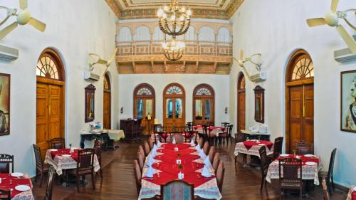 a dining room with tables and chairs and a chandelier at Neemrana's - Baradari Palace in Patiāla