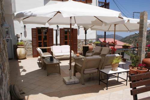 a patio with chairs and a white umbrella at ATRATSA Mountain Suites in Kalopanayiotis
