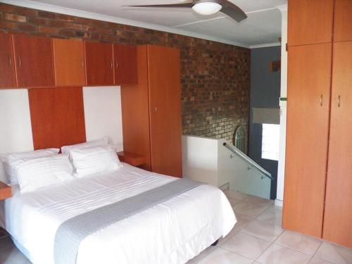 a bedroom with a white bed and a brick wall at 26 Pelser Plaat Meerensee in Richards Bay